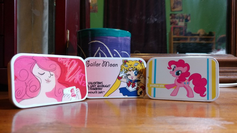 Photo of three small tea tins, one with Rose Quartz from Steven Universe on the front, another with Sailor Moon, and the third with Pinkie Pie from My Little Pony.