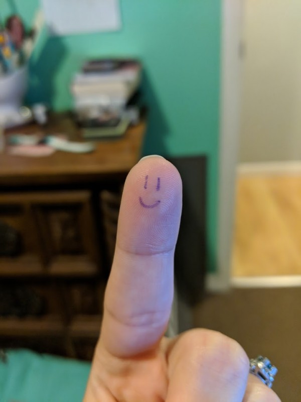 Pointer finger with a smiley face drawn onto it.